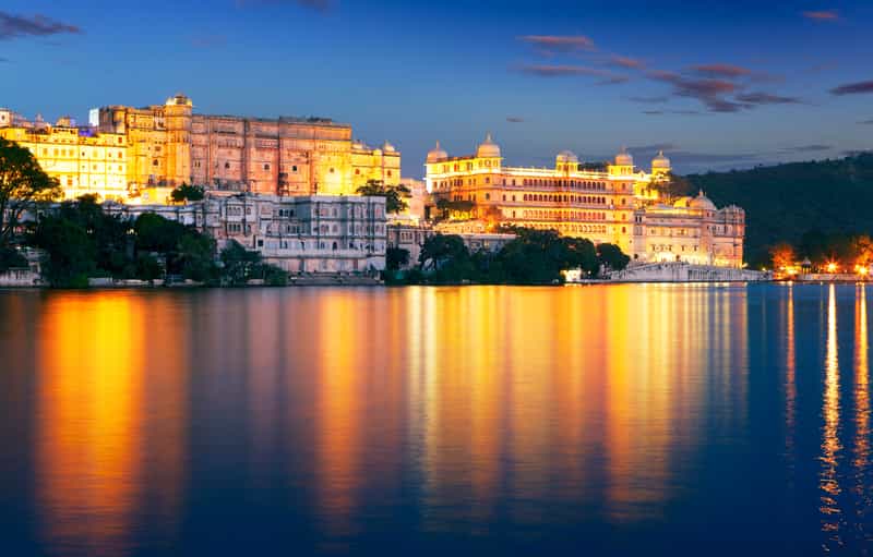 Udaipur City Palace illuminated at night seen from Lake Pichola